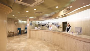 A hotel reception area with a counter, chairs, and a sign for 'CLOAK'.