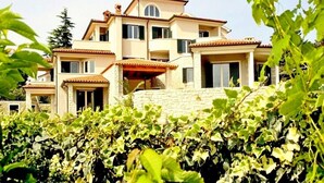 A multi-story residential building with a stone facade, multiple balconies, and a tiled roof. - Apartments Salu (Medulin)