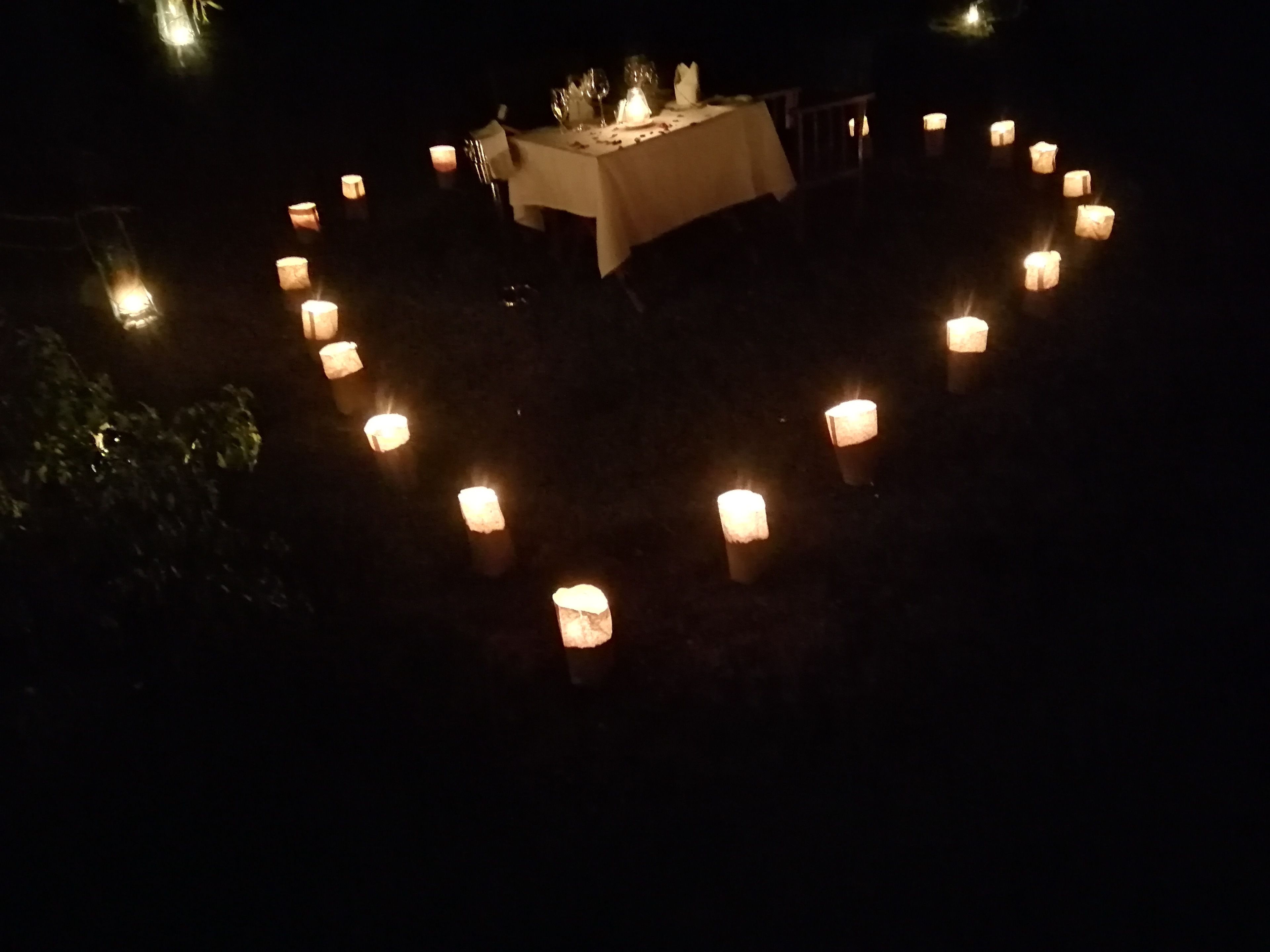 Velas dispuestas en círculo sobre una mesa con mantel, evocando un ambiente romántico o íntimo.