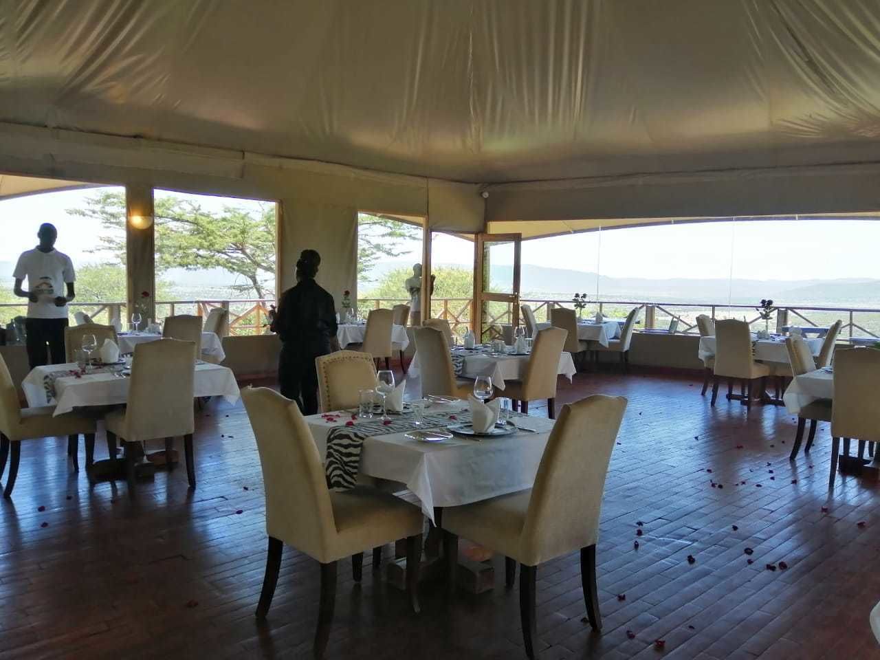 A tented dining area with tables set for a meal, overlooking a scenic landscape.