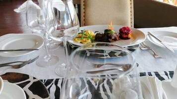 A dining table set with plates, cutlery, and wine glasses, with a zebra-patterned table runner.