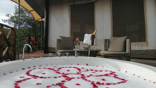A spa area with a large hot tub surrounded by wicker furniture and a pergola.