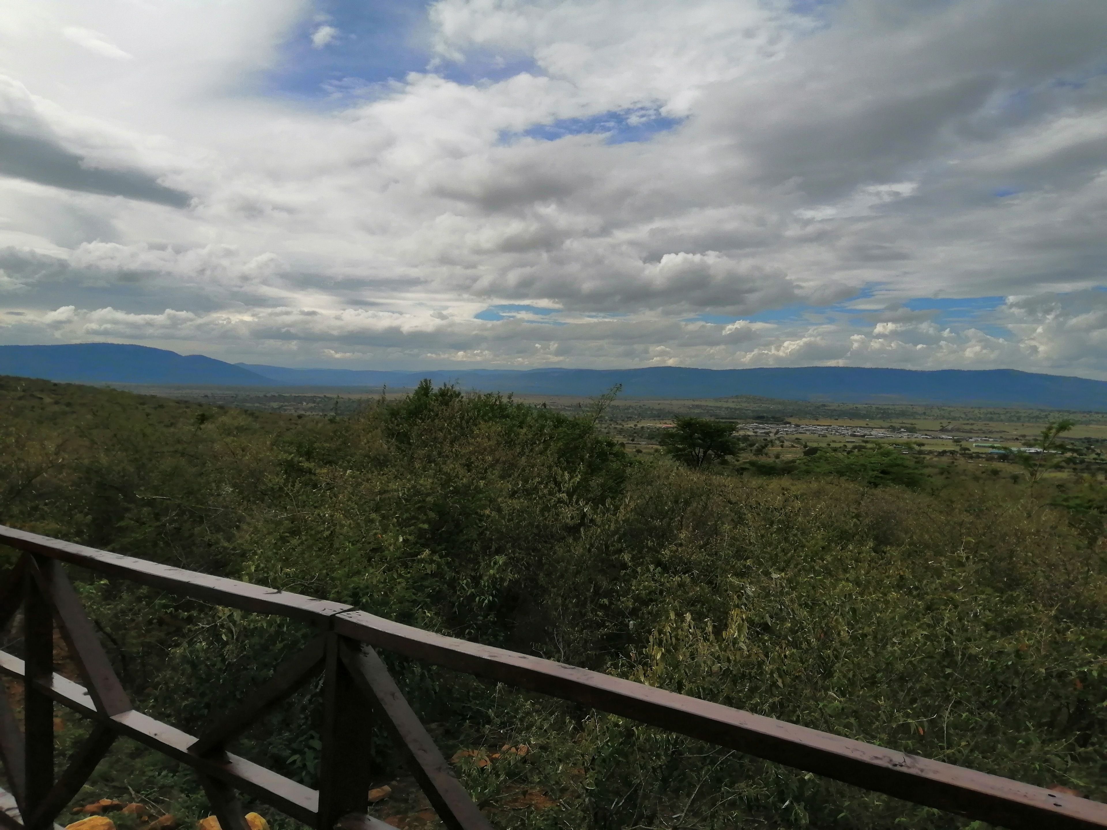 A view from a wooden observation deck overlooking a landscape with distant mountains and a cloudy sky.