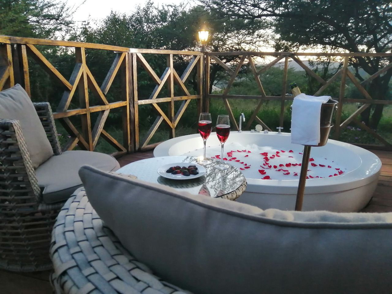 An outdoor seating area with wicker furniture, a hot tub, and rose petals.