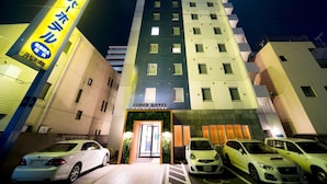 A multi-story hotel with a prominent sign and several parked cars in front. - Super Hotel Takamatsu Kinenkan (Takamatsu)