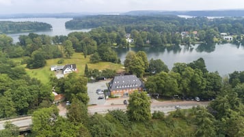 An aerial view of a lakeside property with a large house, a parking area, and surrounding greenery.