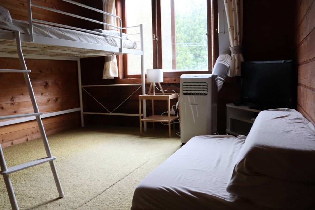 A bunk bed room with a desk, chair, and a television.