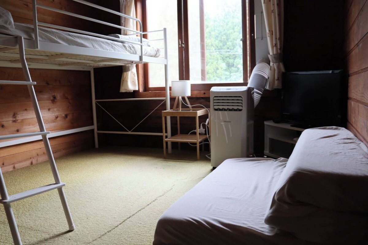 A bunk bed room with a desk, chair, and a television.