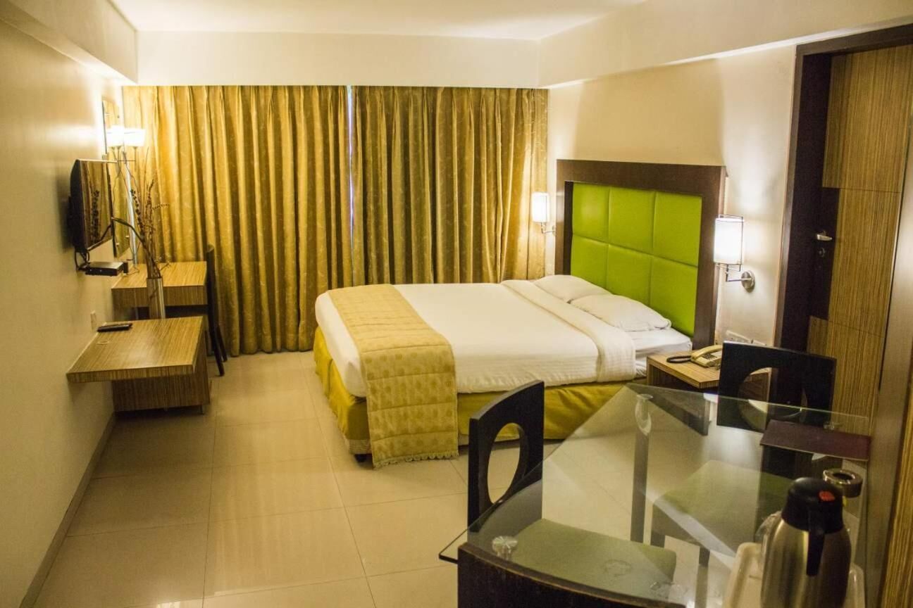 A hotel room with a bed, a desk, a chair, a table, and a television.