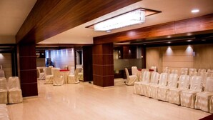 A spacious hall with rows of chairs and a stage, wooden paneling, and a chandelier.