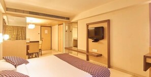 Une chambre d’hôtel avec un lit, un téléviseur fixé au mur, une petite table et une chaise.