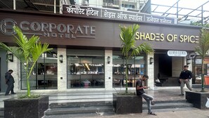 A hotel with a modern facade, featuring a prominent sign for "Corporate Hotel" and "Shades of Spice".