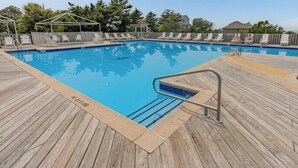 Une terrasse en bois entoure une piscine rectangulaire, à laquelle on accède par une échelle en métal.