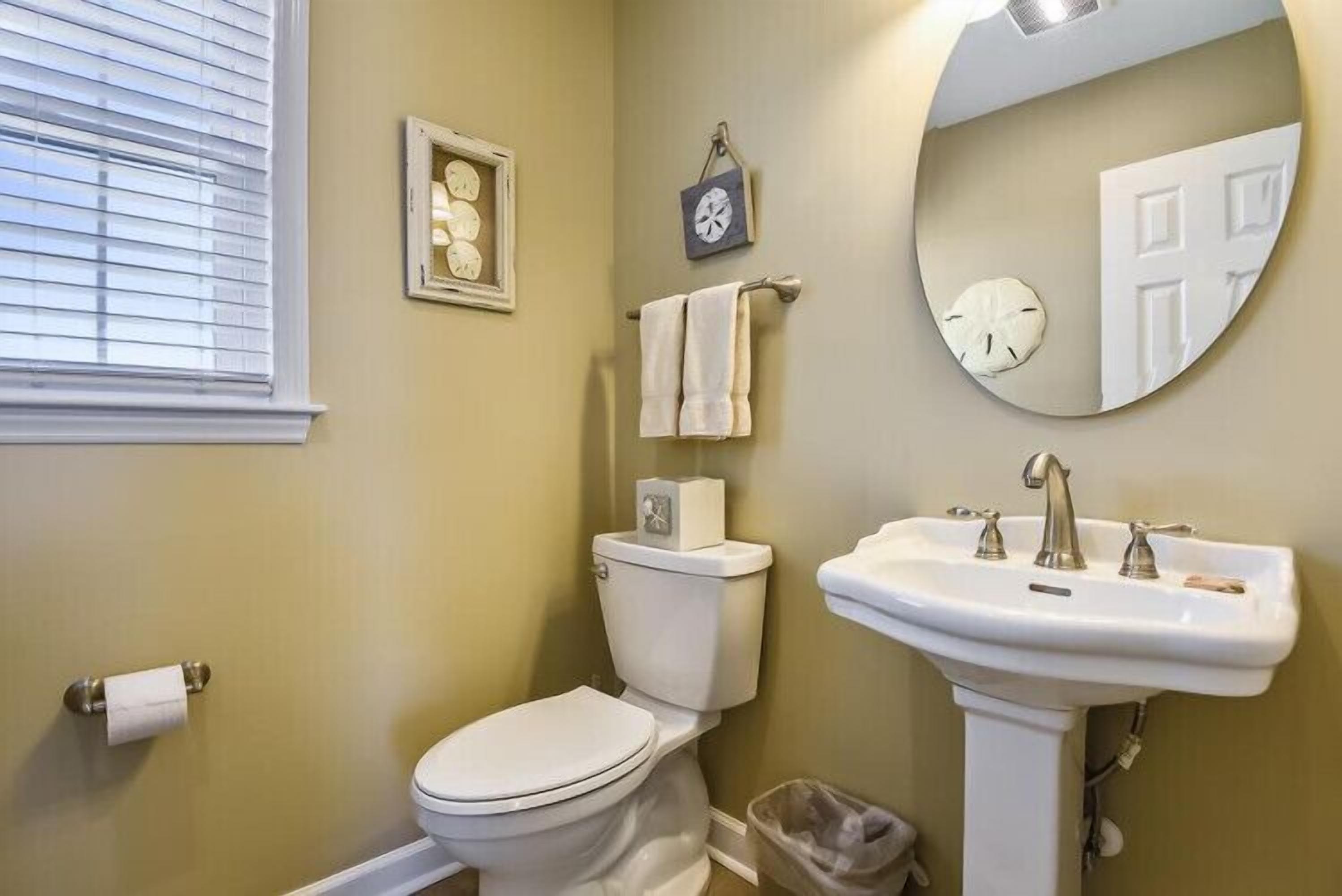 A bathroom with a toilet, sink, and a window with blinds.