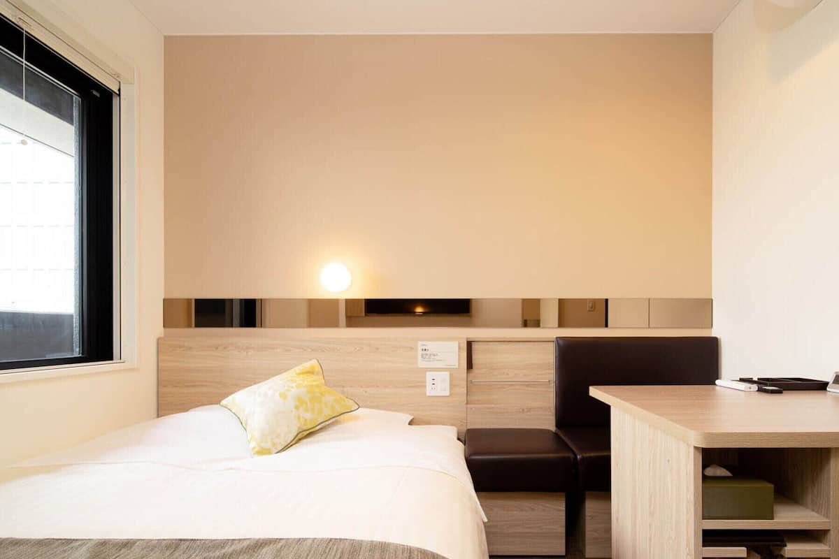 A compact hotel room with a bed, a desk, and a chair.