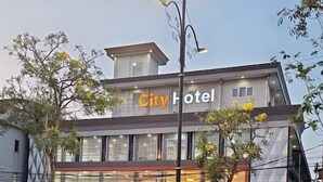 A modern city hotel with a prominent 'City Hotel' sign, large windows, and a well-maintained outdoor area with plants. - Capital O 769 City Hotel (Balikpapan)