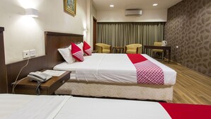 A hotel room with a bed, bedside table with a phone, two chairs, a small table with a kettle, and a curtain backdrop. - Capital O 769 City Hotel (Balikpapan)