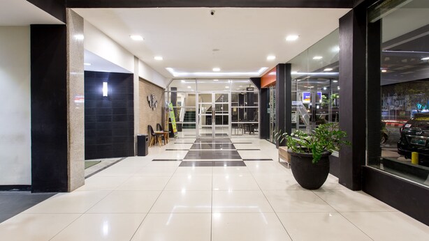 A modern lobby with a checkered floor pattern, a large potted plant, and a glass entrance leading to an interior space. - Capital O 769 City Hotel (Balikpapan)