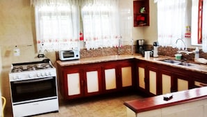A kitchen with a stove, microwave, and sink. - Casa em Campos do Jordão (Campos do Jordão)