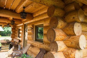 A log cabin with a wooden exterior, a bench, a table, and a window. - Apartments and wellness center Korošec (Mozirje)