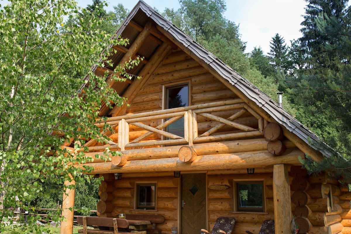 Une cabane en rondins avec une véranda, une fenêtre et une porte.