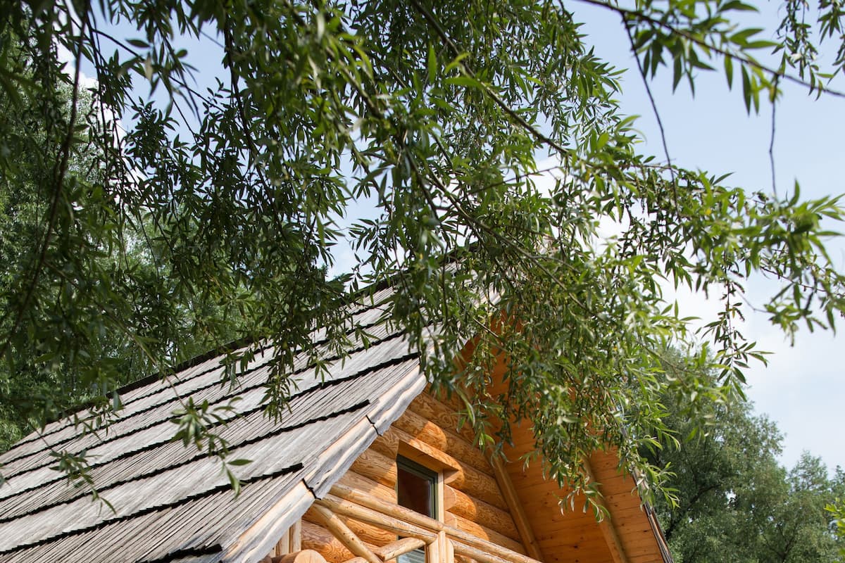 Une cabane en rondins avec un porche, des bancs verts et une table de pique-nique.