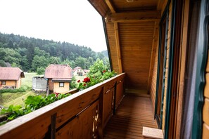 A wooden balcony with a view of houses and greenery. - Apartments and wellness center Korošec (Mozirje)