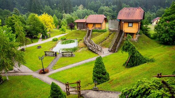 Ein rustikales Blockhaus mit Holzfassade, einem Kiesweg und einem kleinen Teich.