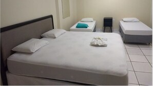 A hotel room with a large bed, two smaller beds, a nightstand, and a mirror on the wall. - Hotel Boa Viagem (Barra do Garcas)