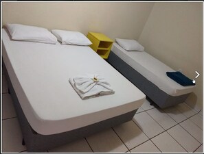 A room with a large bed, a smaller bed, a yellow storage unit, and a bedside table with a pillow. - Hotel Boa Viagem (Barra do Garcas)