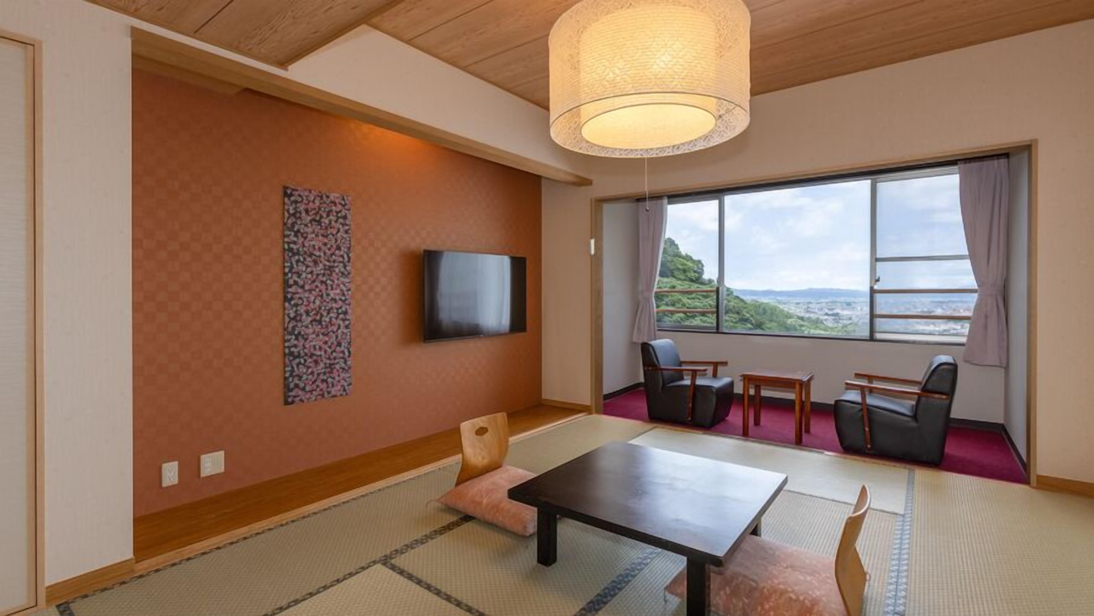 Een kamer met een televisie, een bank, een tafel en stoelen.