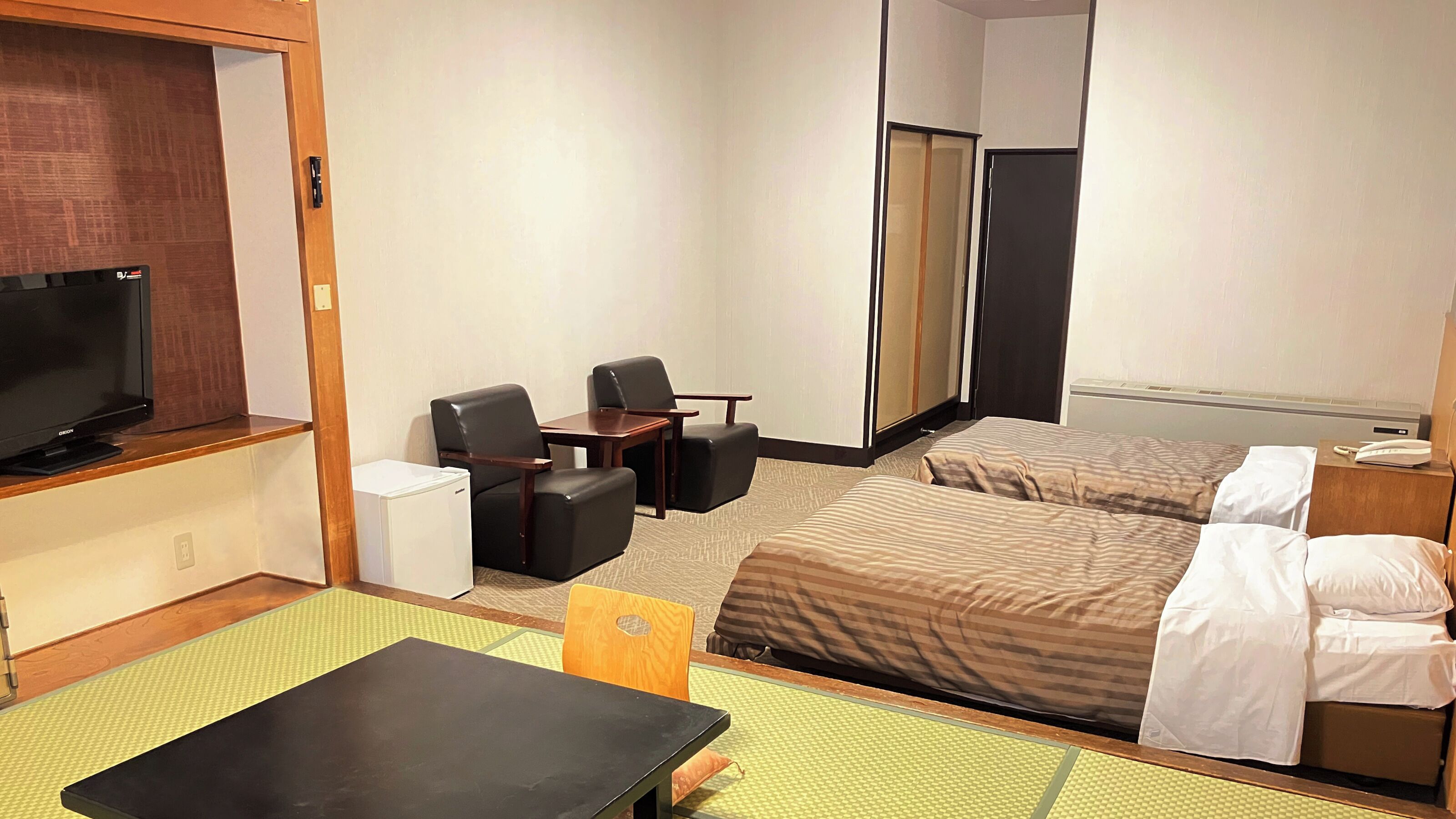 Habitación de hotel con cama, escritorio, silla, televisor y armario.