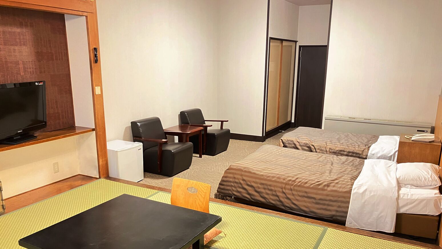 Una habitación de hotel con una cama, un escritorio con una silla, un televisor y un armario.
