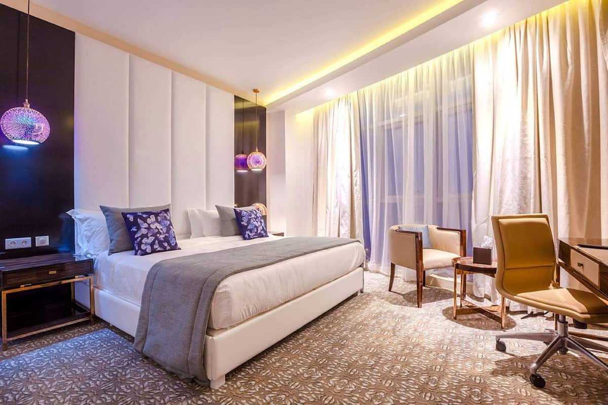 A hotel room with a large bed, bedside tables, a desk, and a chair.