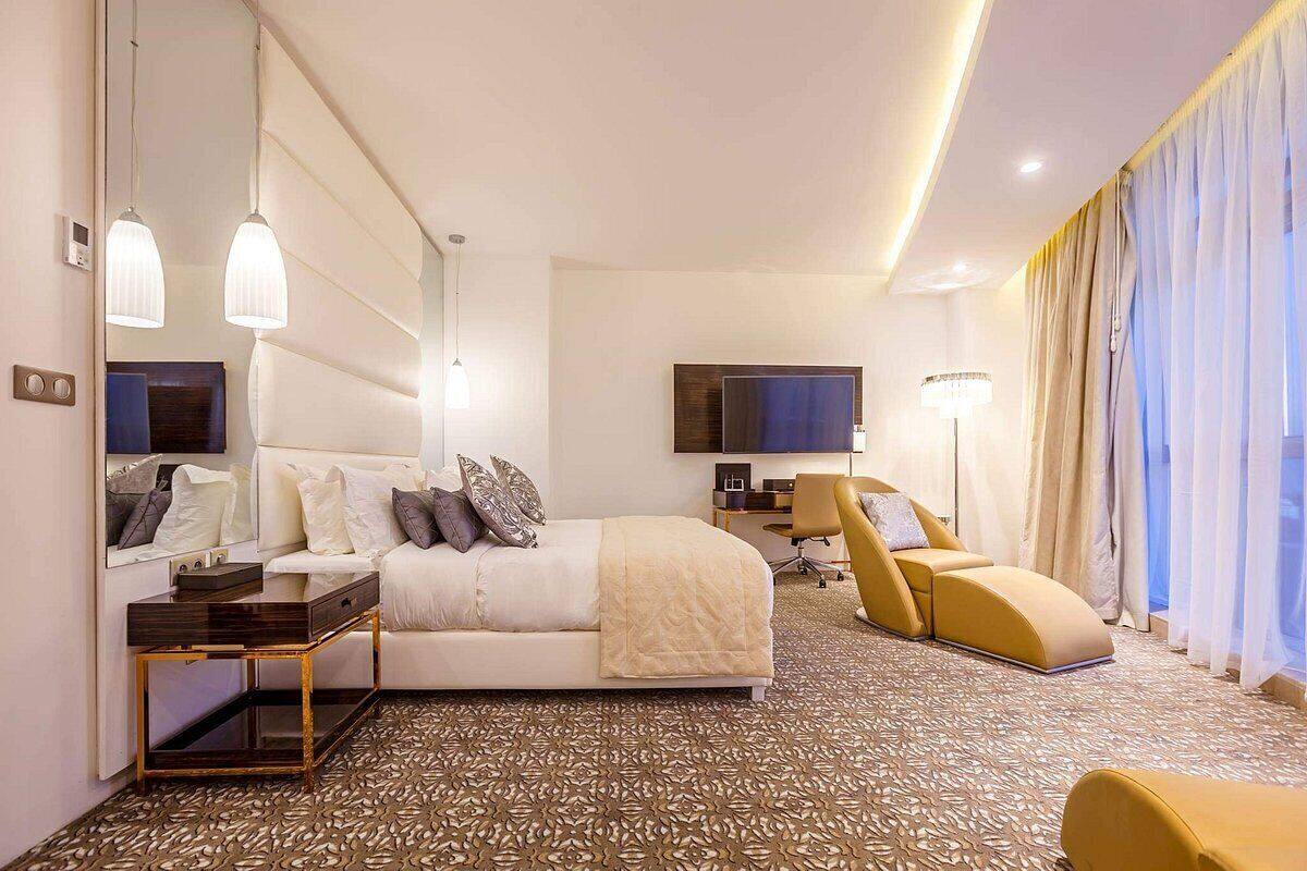 A modern hotel room with a large bed, a desk, a sofa, and a TV.