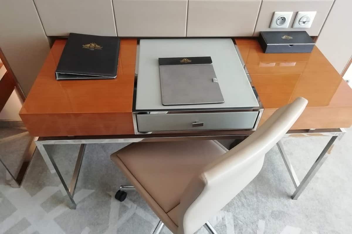 A modern office desk with a leather chair, a black folder, and a grey folder on it.