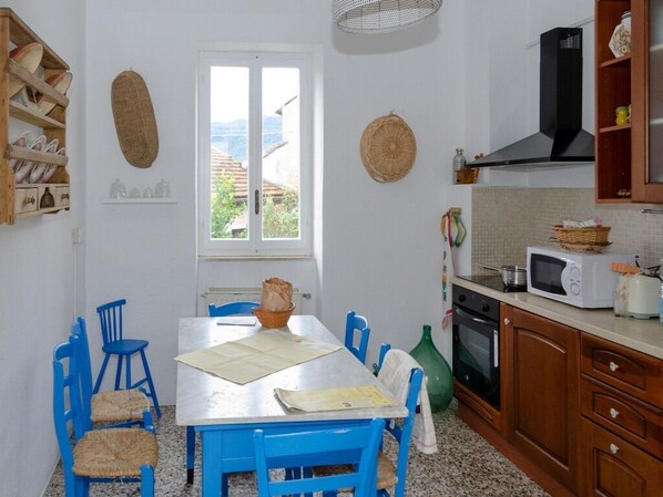 Un área de comedor con una mesa y sillas, una ventana con vistas, microondas y estufa.