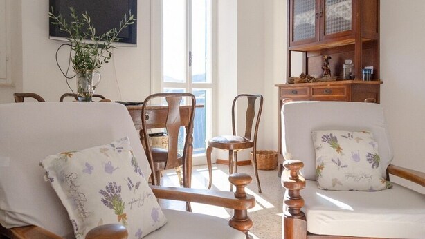 A living room with two wooden chairs, a wooden cabinet, and a vase with plants.