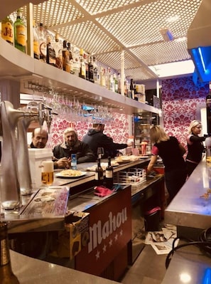 Enjoy a refreshing drink at the bar, where a geometric ceiling and floral wallpaper create a unique atmosphere.