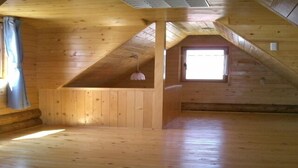 A spacious attic room with wooden walls and a sloped ceiling.