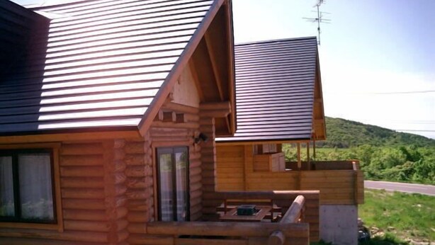 A wooden cabin with a sloped roof, a balcony, and a window.