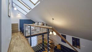 Un interior modern amb una escala de fusta, lluminàries superiors i una zona de dinar.