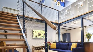 Un interior modern amb una escala de fusta, un sofà blau i una zona de cuina.