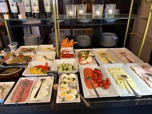 Un bufé con diversas opciones de comida, como pasta, ensaladas, quesos y carnes.