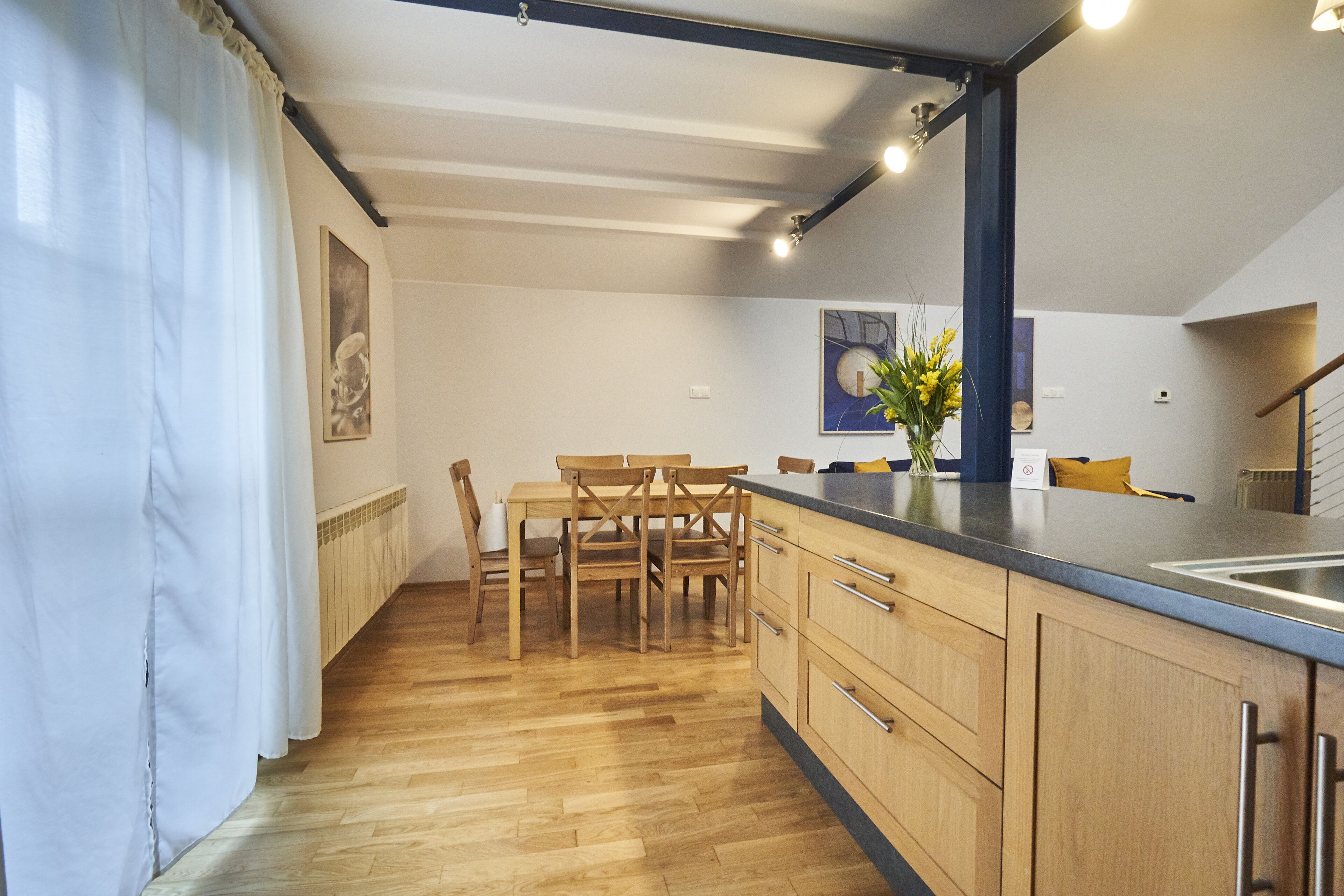Een moderne keuken met houten kastjes, een eettafel met stoelen en een groot schiereiland met een spoelbak.