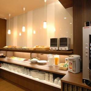 Een buffetgedeelte met diverse etenswaren, een koffieapparaat en een koelkast.
