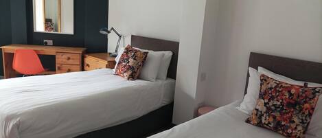A hotel room with two beds, a desk, and a chair.