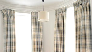 A room with two orange armchairs, a round glass table, plaid curtains, and a ceiling light. - Tom Dick and Harriet's (Dublin)