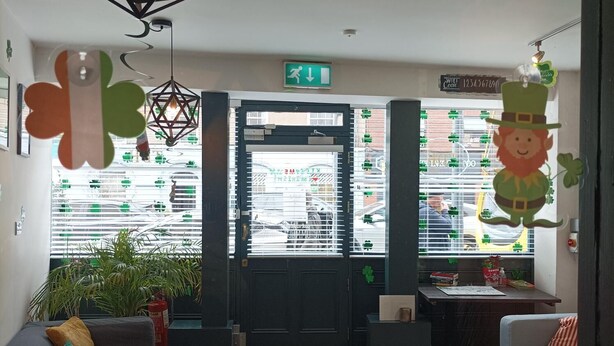 A cozy hotel lobby with a reception desk, seating area, and a view of the street outside. - Tom Dick and Harriet's (Dublin)