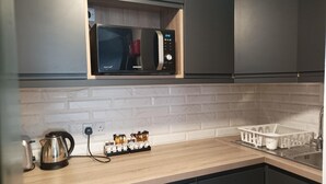 A modern kitchen with a microwave, kettle, and tea/coffee dispenser on the counter. - Tom Dick and Harriet's (Dublin)